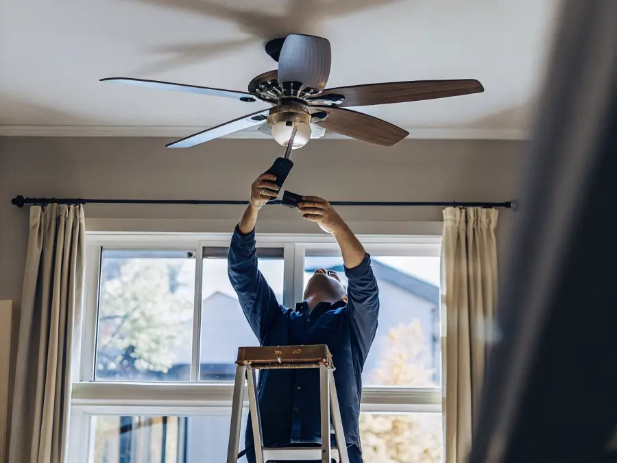 Electrician on a step ladder installing a ceiling fan