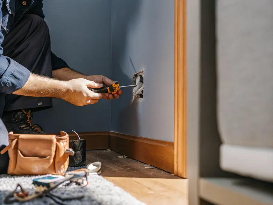 Electrician replacing a wall outlet with the cover plate removed